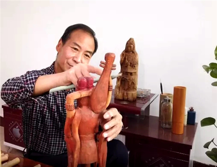 赵德成眼神专注，手中的刻刀在木板上熟练游走.jpg