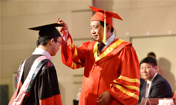 Yun Guohong (R), president of IMNU arranges the tassel on the graduation cap of a graduate during the ceremony held at IMNU on July 3..jpg
