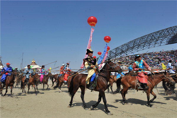 A squad of horseracing jockeys trot into the opening ceremony of the 24th Tourism Naadam Festival 