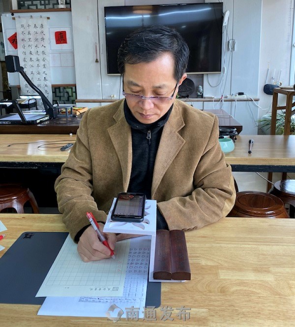 ao Bin, a calligraphy teacher in Chongchuan district, Nantong, Jiangsu province, records a teaching video for his students during the fight against coronavirus.jpg
