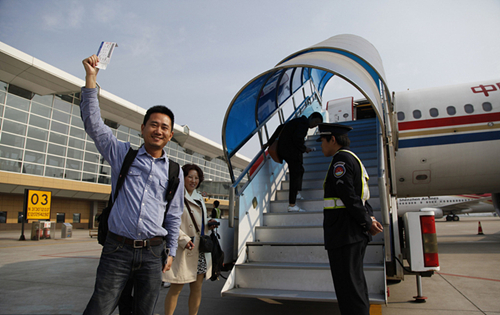 2013年5月5日，在江苏无锡苏南硕放国际机场，一名旅客在登机前挥舞登机牌。.jpg