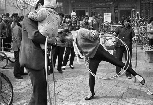 1990s《呼啦圈》紧身裤真新潮 九十年代初，一种叫呼啦圈的健身用具风靡社会。这位卖呼啦圈的时髦女子在南京街头一边吆喝一边玩，性感的踩脚裤取代了曾经流行的喇叭裤成为新潮。作者：田鸣.jpg