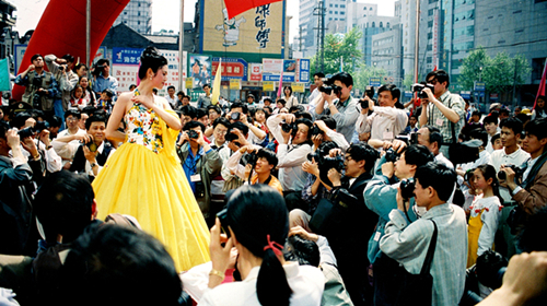 2004《街头时装秀》2004年10月摄于镇江市大市口。 时装秀从室内丅台走向大街，时装模特被大批使用㬵片相机的摄影者拥簇着，犹如“众星拱月”。作者：佘佳虎.jpg