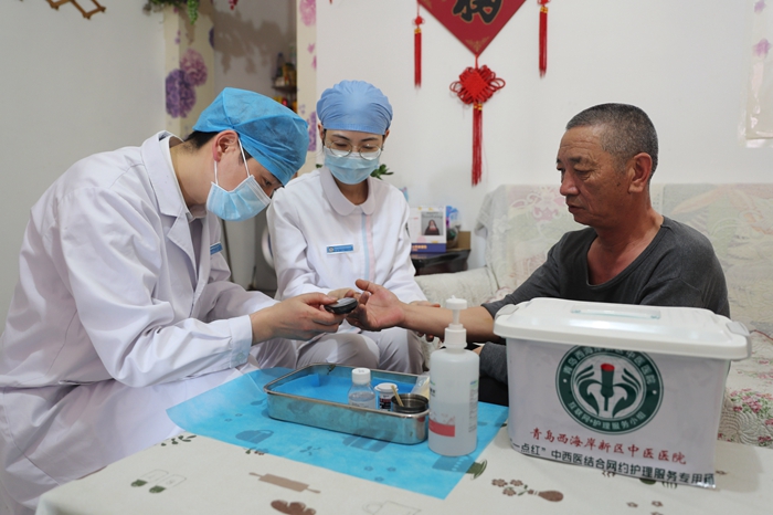 07 3月14日，青岛西海岸新区中医医院网约护士赵品会（左一）和管洨在为患者进行血糖检测。 (张进刚 摄2)电话13854260100.jpg