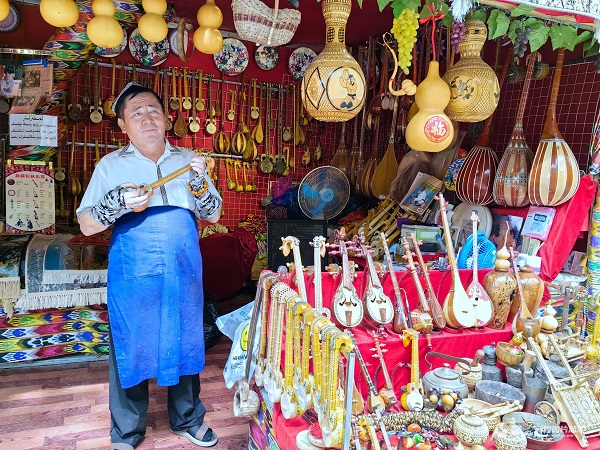 苏力坦·马木提在葡萄沟景区向游客展示自己制作的乐器。（摄影：管梦颖）.jpg