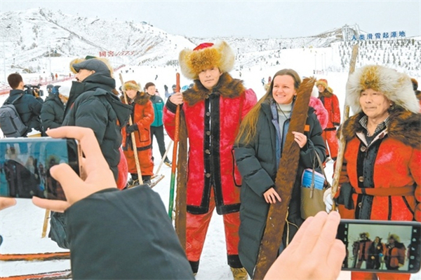 11月25日，在阿勒泰将军山国际滑雪度假区，上合组织秘书处官员伊丽莎白·切尔内舍娃与古老毛皮滑雪队队员合影留念。（摄影：谢龙）.jpg